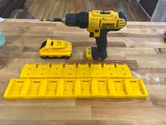 a drill and screwdriver sitting on top of a wooden table next to some plastic blocks