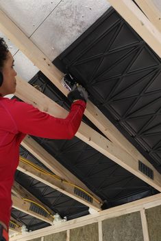 a woman in red shirt working on ceiling