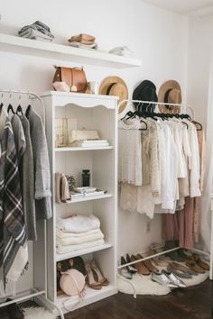 a white closet filled with lots of clothes and hats on top of shelving units