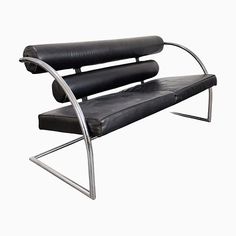 a black leather and chrome bench with curved back rests against a white background in the foreground