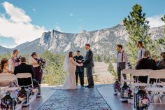 a bride and groom standing at the end of their wedding ceremony with mountains in the background