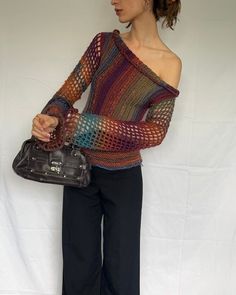 a woman is holding a handbag and posing for the camera in front of a white backdrop