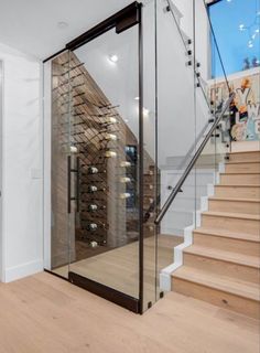 a glass staircase leading up to a wine cellar in the middle of a room with white walls and wooden floors