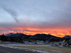 the sun is setting over some mountains in the distance, with snow on the ground