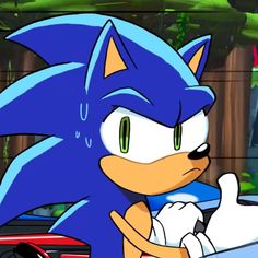 sonic the hedge is driving in front of a red car with his hand on his hip