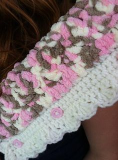 a woman wearing a crocheted scarf with pink and brown flowers on it's back