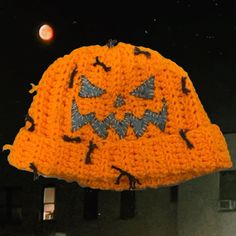 a crocheted pumpkin hat hanging from a hook on a window sill at night