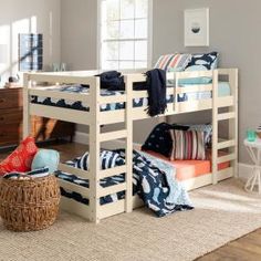 a bedroom with bunk beds and pillows on the bottom bunk, next to a wicker basket