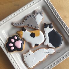 decorated cookies in the shape of dogs and cats on a plate with white trimmings