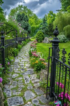 a stone path leads to a lush green garden with flowers and trees on either side