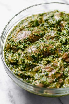 a glass bowl filled with pesto and meat