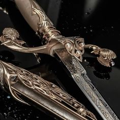 an elaborately designed knife is sitting on a black surface with water droplets around it