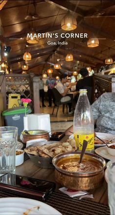 a table full of food and drinks with people sitting at the tables in the background