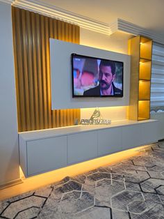 a flat screen tv mounted to the side of a wall in a room with gold and white walls