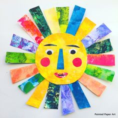 a paper plate sun craft with colorful strips on the bottom and face painted in different colors