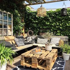 an outdoor living area with couches, tables and potted plants