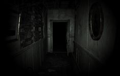 a dark hallway with an open door leading to another room