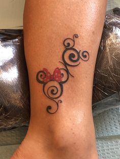 a woman's foot with a minnie mouse tattoo on her left leg and red bow at the top