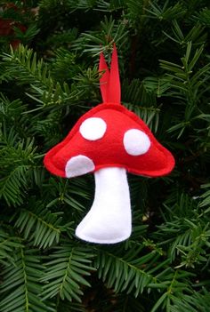 a red and white mushroom ornament hanging from a tree