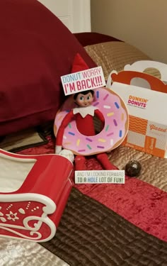 an elf with a donut in his hand on a bed next to some boxes