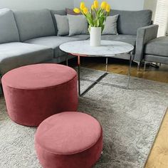 a living room with grey couches and pink ottomans