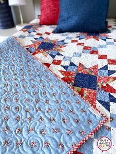 a bed with blue and red quilts on it