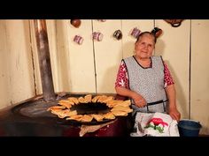 an older woman standing in front of a stove with chips on the table next to it