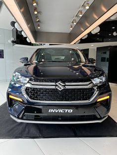 the front end of a black car in a showroom