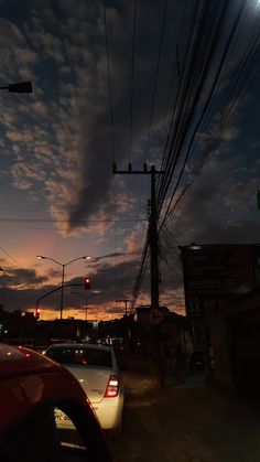 some cars are parked on the side of the road at night with clouds in the sky