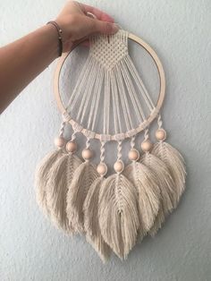 a person is holding up a wall hanging with beads and tassels on it