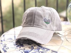 Need to change this cap design to a messy bun/high ponytail cap style, a non-distressed baseball cap or kid's baseball cap?  Once you have this cap in your cart, head here: https://etsy.me/2S82fka Distinct Headwear Presents... Embroidered Women's Thin Green Line Hat Main photo shows a light grey cap. Choose your cap color. Not a patch, all direct embroidery. Need a different line color? Click here: https://etsy.me/2wJA8PP CAP FEATURES: -Women's fit, 100 percent washed cotton distressed cap. -Will fit most teens/adult females. -Cap base is significantly more expensive than your typical Etsy seller uses for embroidery. -Soft and unstructured fabric (not a stiff/hard cap). -Faux/vegan leather, adjustable buckle back. -Custom designed embroidered onto cap - no patches or vinyl. STRAP SIZING: Bun High, Ponytail Cap, Kids Baseball Caps, Distressed Baseball Cap, Gray Cap, Fall Hats, Clothing Cute, Cap Designs, High Ponytail