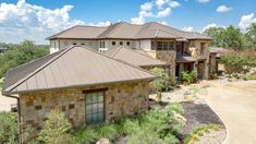 an aerial view of a house with stone and metal roofing in the foreground