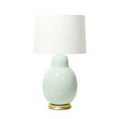 a light green table lamp with a white shade on the base and a gold metal base