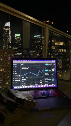 an open laptop computer sitting on top of a desk in front of a large window