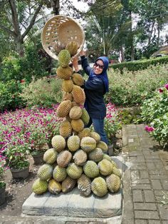 a woman standing next to a pile of fruit on top of a stone slab in a garden