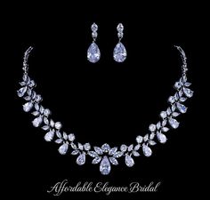 a necklace and earring set with pear shaped diamonds on the front, in white gold