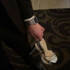 a man in a tuxedo is tying his high - heeled shoes with a watch on his wrist