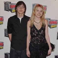 two people standing next to each other on a red carpet