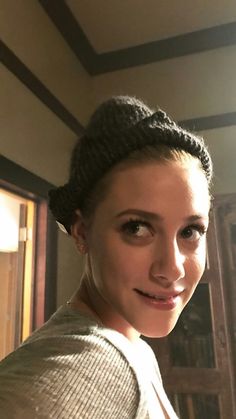 a young woman is smiling and posing for the camera with her hair in a bun