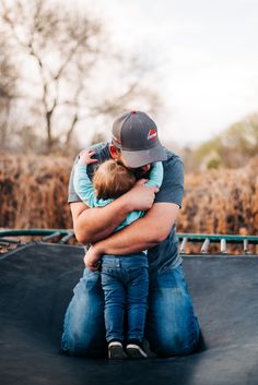 a man holding a child on top of a skateboard ramp