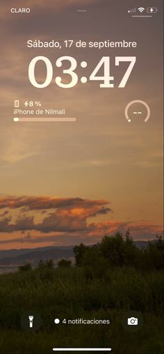 an image of the clock displayed on a cell phone with sunset in the back ground