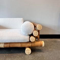 a white couch sitting on top of a wooden frame next to a gray wall and floor