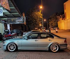 a silver car parked on the side of a street next to a building at night