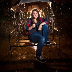 a woman sitting on a bench in the rain with an umbrella over her head,