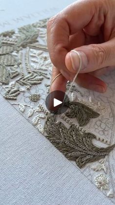 someone is working on an embroidered piece with thread and beads in the middle of it