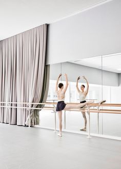 two ballerinas standing in front of a mirror with their arms up and hands behind them