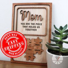 a wooden puzzle with the words mom on it and a potted plant next to it