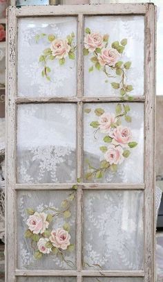 an old window with flowers painted on the glass is displayed in front of a table