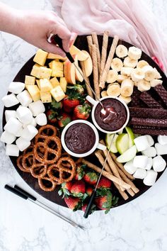 a platter with pretzels, strawberries, apples, chocolate and marshmallows