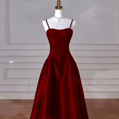 a mannequin dressed in a red dress on a wooden floor next to a white wall